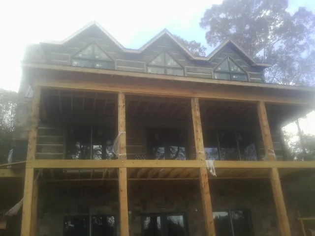 Dormers and porch framing on a large log home under construction — Roof Coating work by our crew in Toddville