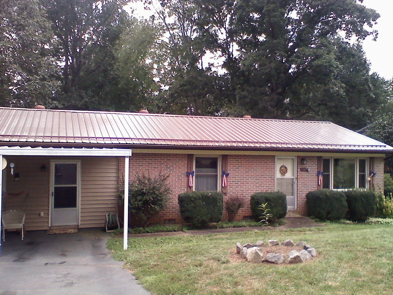 Bronze metal roof and carport on a brick ranch home — Roof Repair work by our crew in Toddville